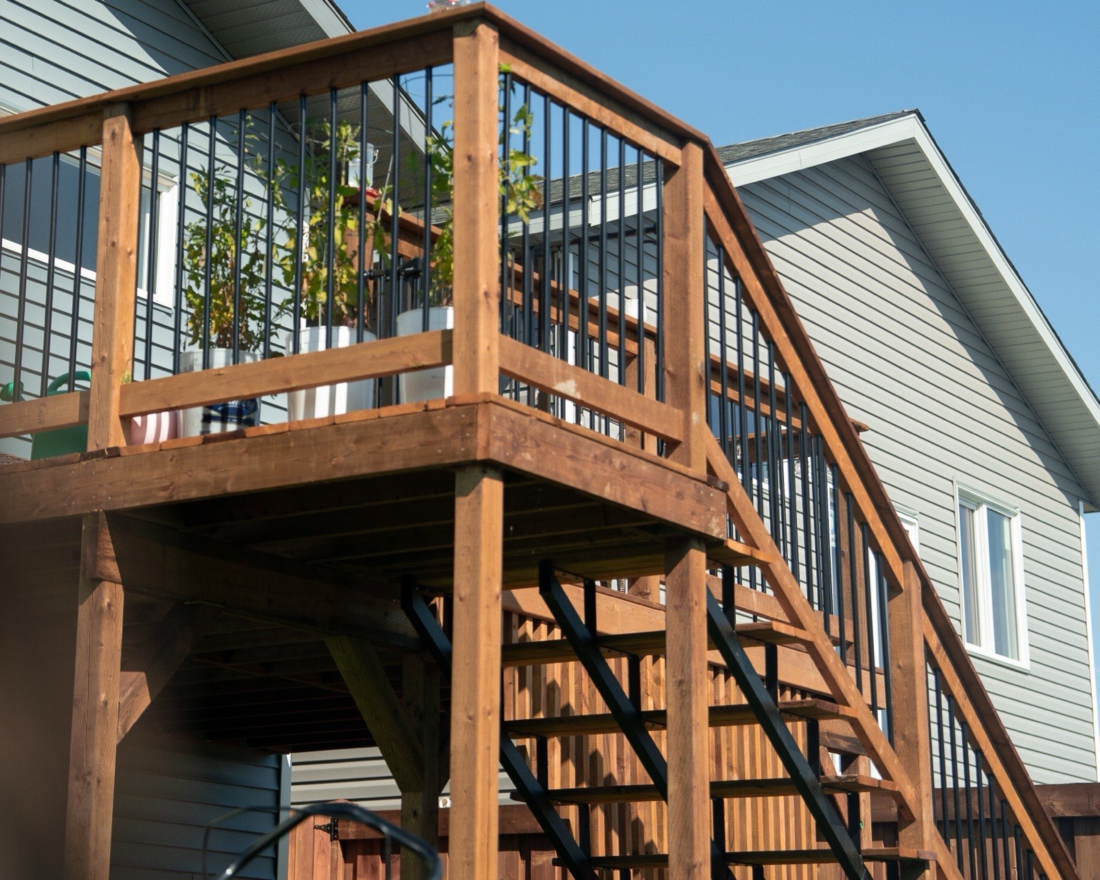 Raised cedar deck with railing and stairs on the side of a house