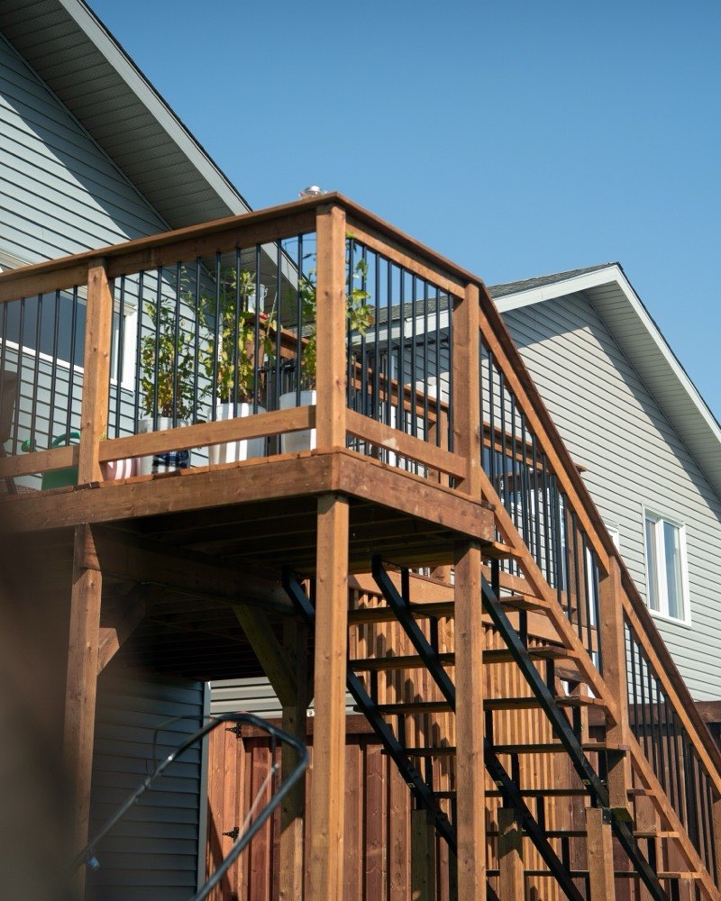 Raised cedar deck with black spindle railing and a full run of stairs