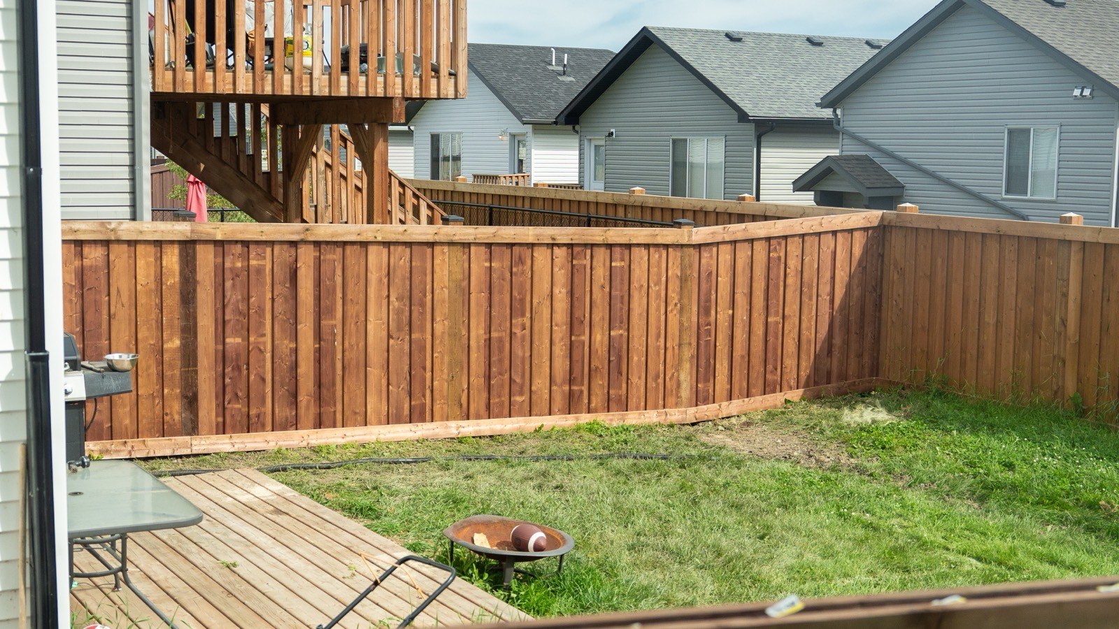 Cedar privacy fence wrapping a backyard with a lawn and patio